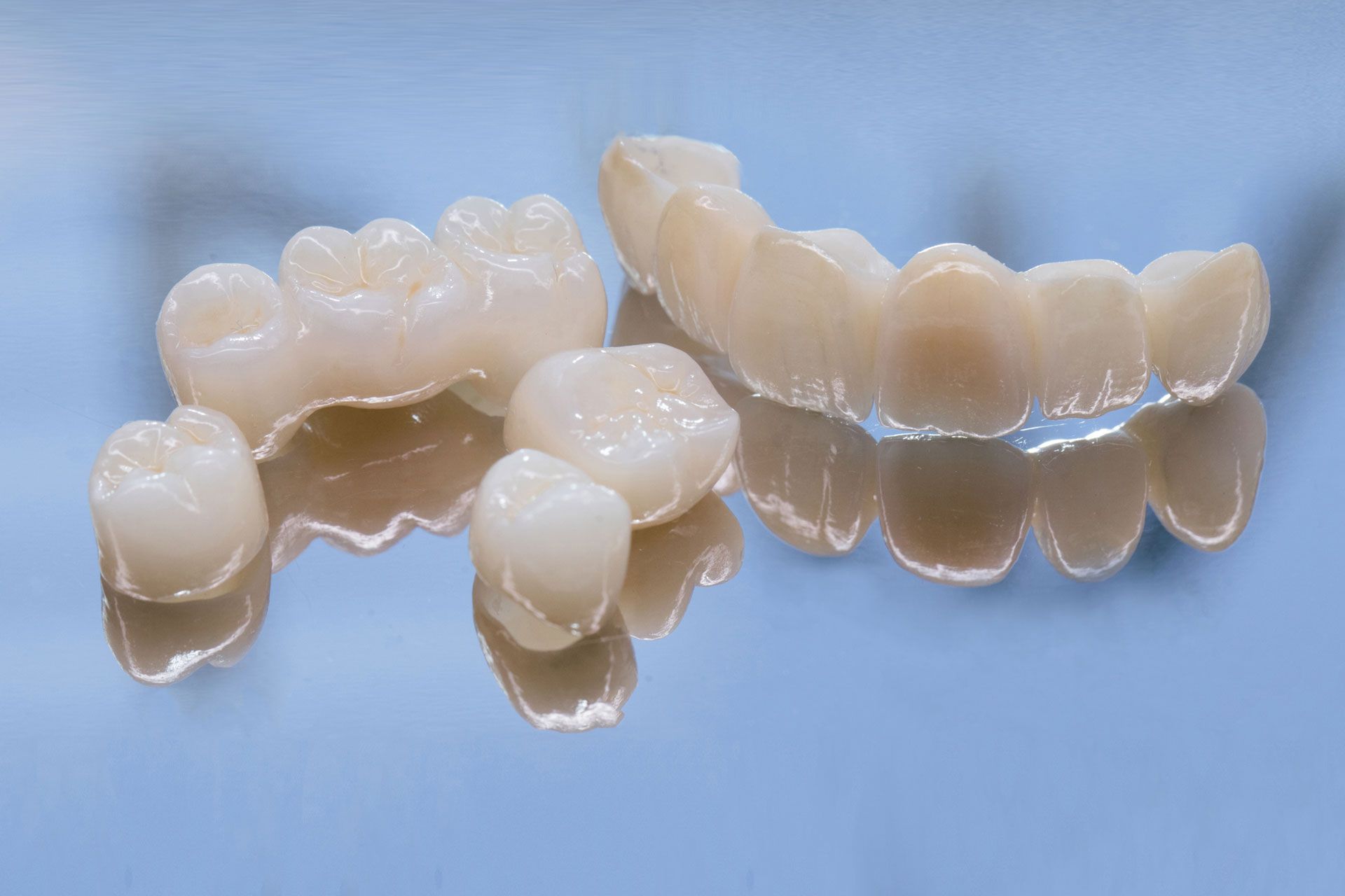 A close up of a pair of dental crowns on a blue surface.