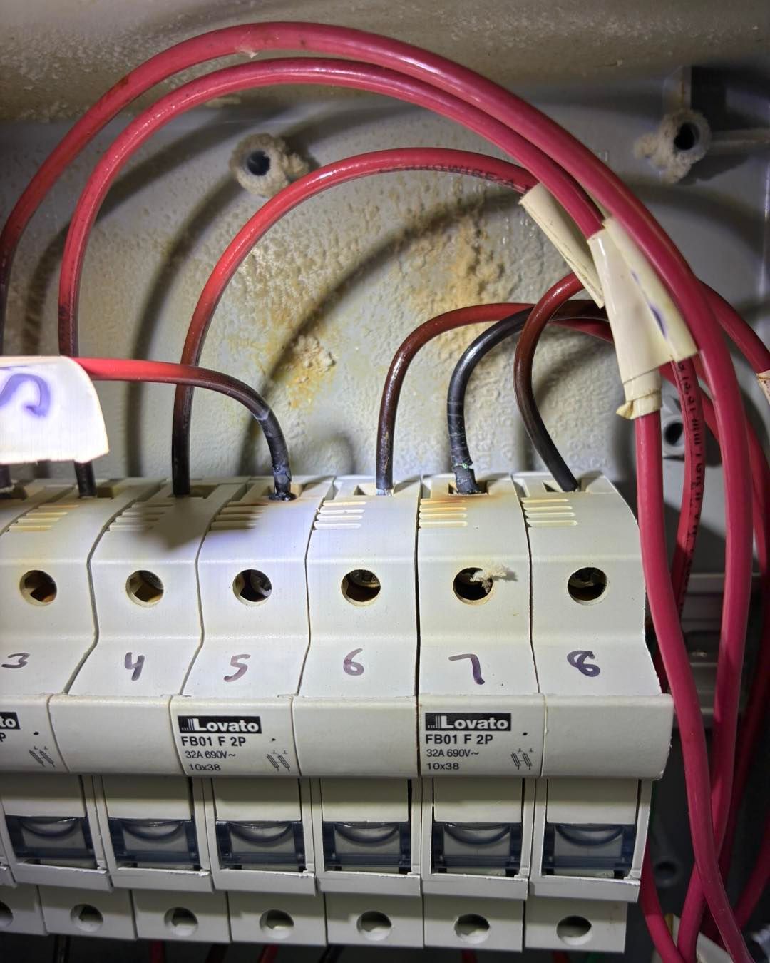 Row of electrical circuit breakers with red and black wires in a panel