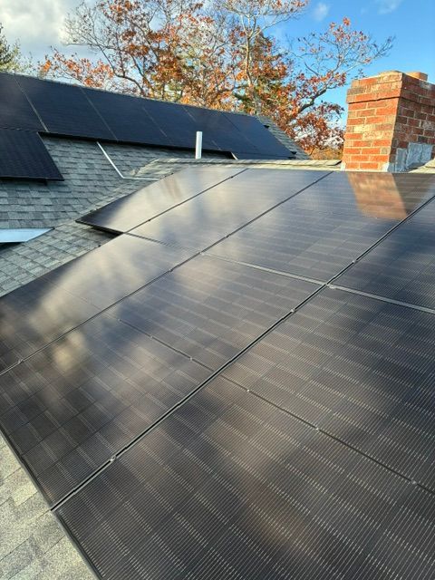 Solar panels mounted on a sloped roof beside a brick chimney under a clear sky