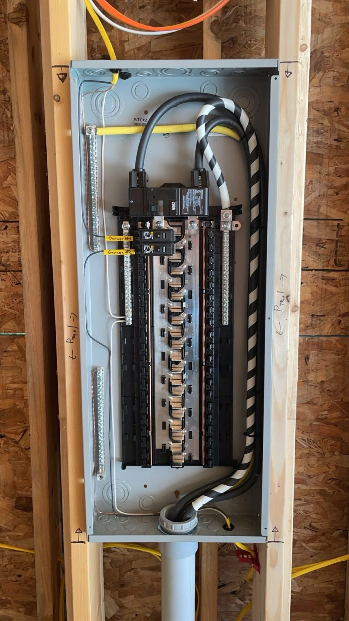 Open electrical breaker panel with wires and circuit breakers mounted in a wall