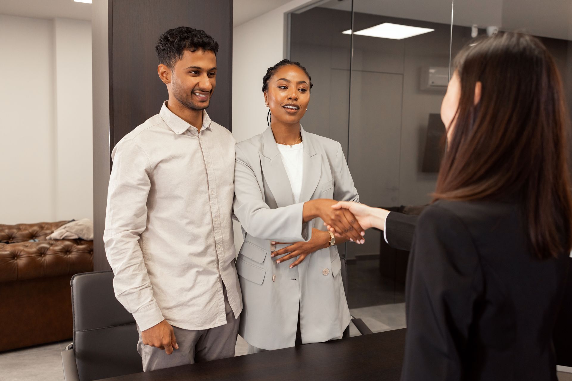 Three people shaking hands in a modern office conference room