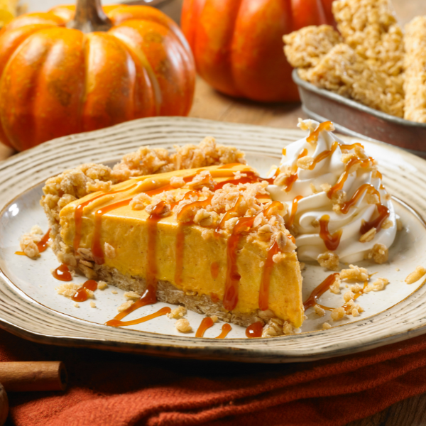 pumpkin spice cheesecake with granola crust topped with caramel, crumble and whipped cream