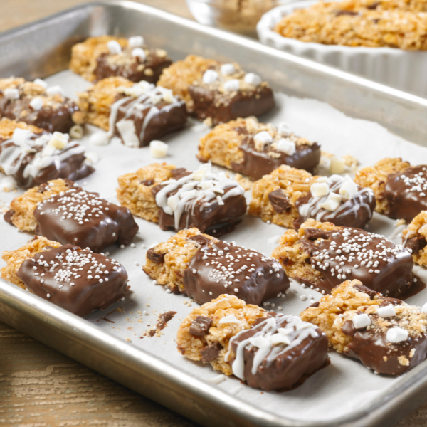 granola bar halves dipped in chocolate and topped with mini marshmallows and white chocolate drizzle