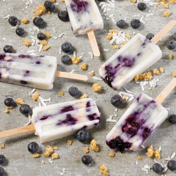 popsicles made with coconut milk, fresh blueberries and coconut cream chewy granola bars on a light background
