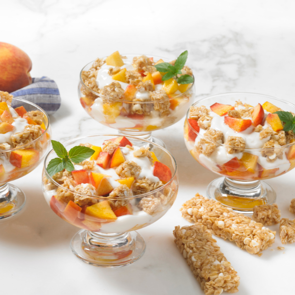 yogurt layered with fresh peaches and granola topped with mint in glasses
