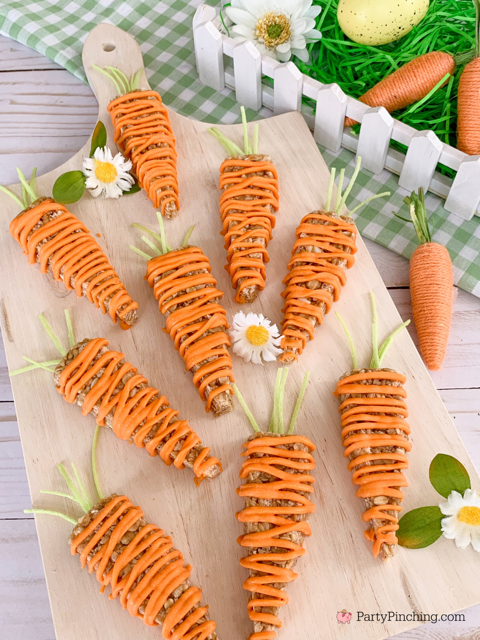 granola bars shaped and decorated like carrots for spring on a wooden board with green gingham and flowers
