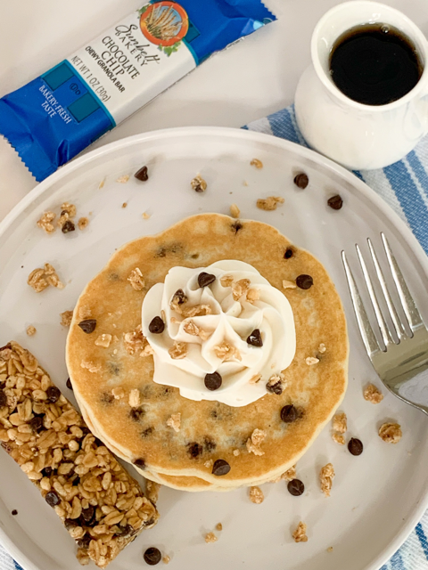 chocolate chip pancakes topped with granola and chocolate chips and whipped cream