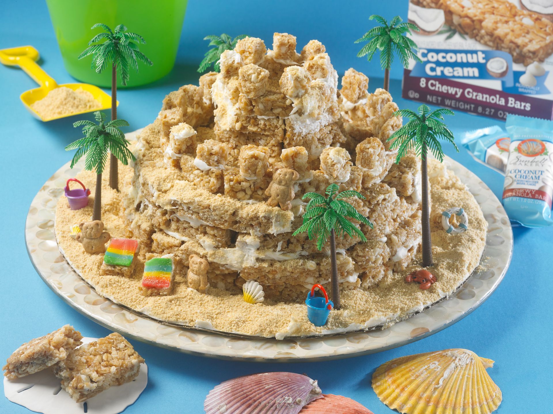 decorative, edible sandcastle made of coconut cream chewy granola bars and decorated with mini beachy decor items