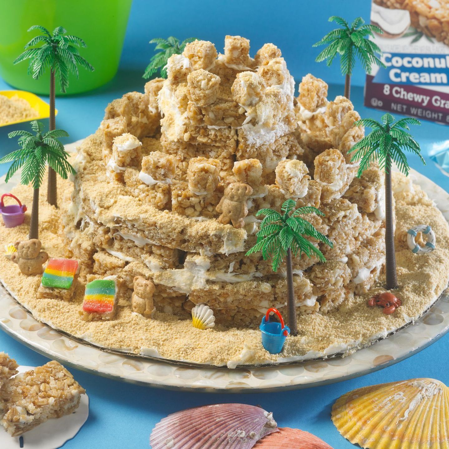 decorative, edible sandcastle made of coconut cream chewy granola bars and decorated with mini beachy decor items