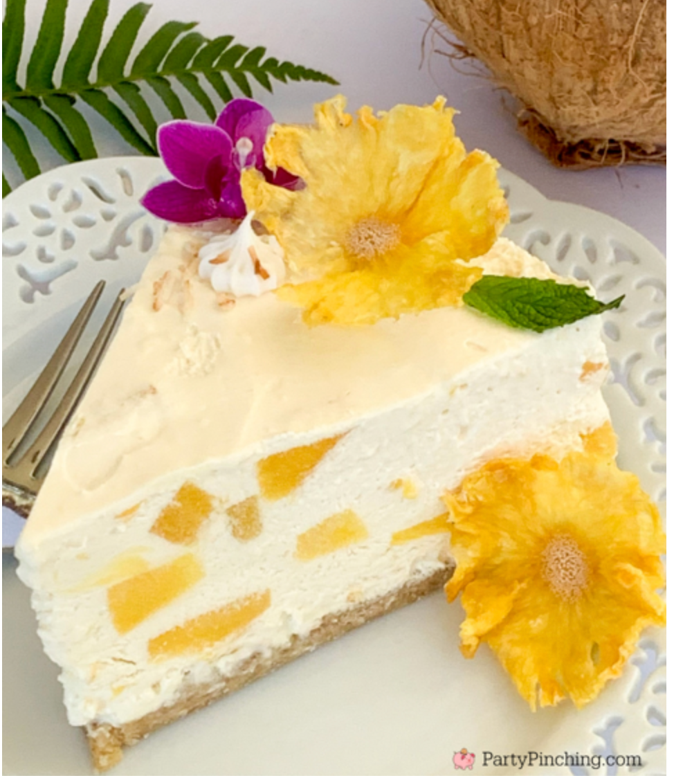 coconut cheesecake with granola crust and topped with tropical flowers on a white plate