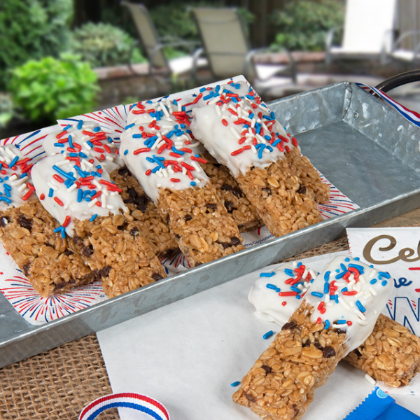 patriotic themed granola bars dipped in white chocolate and topped with sprinkles on a silver serving tray