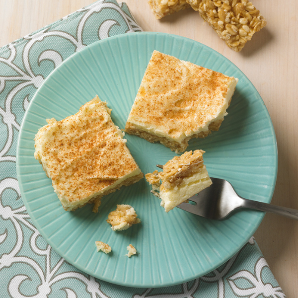 cheesecake bars made of snickerdoodle granola bars and cream cheese frosting on teal plate with napkin