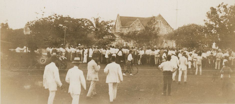 A black and white photo of a group of people walking in a park.