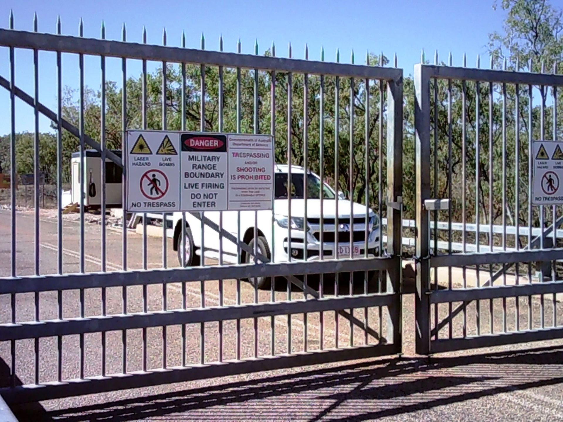 A white truck is parked behind a gate with a danger sign on it