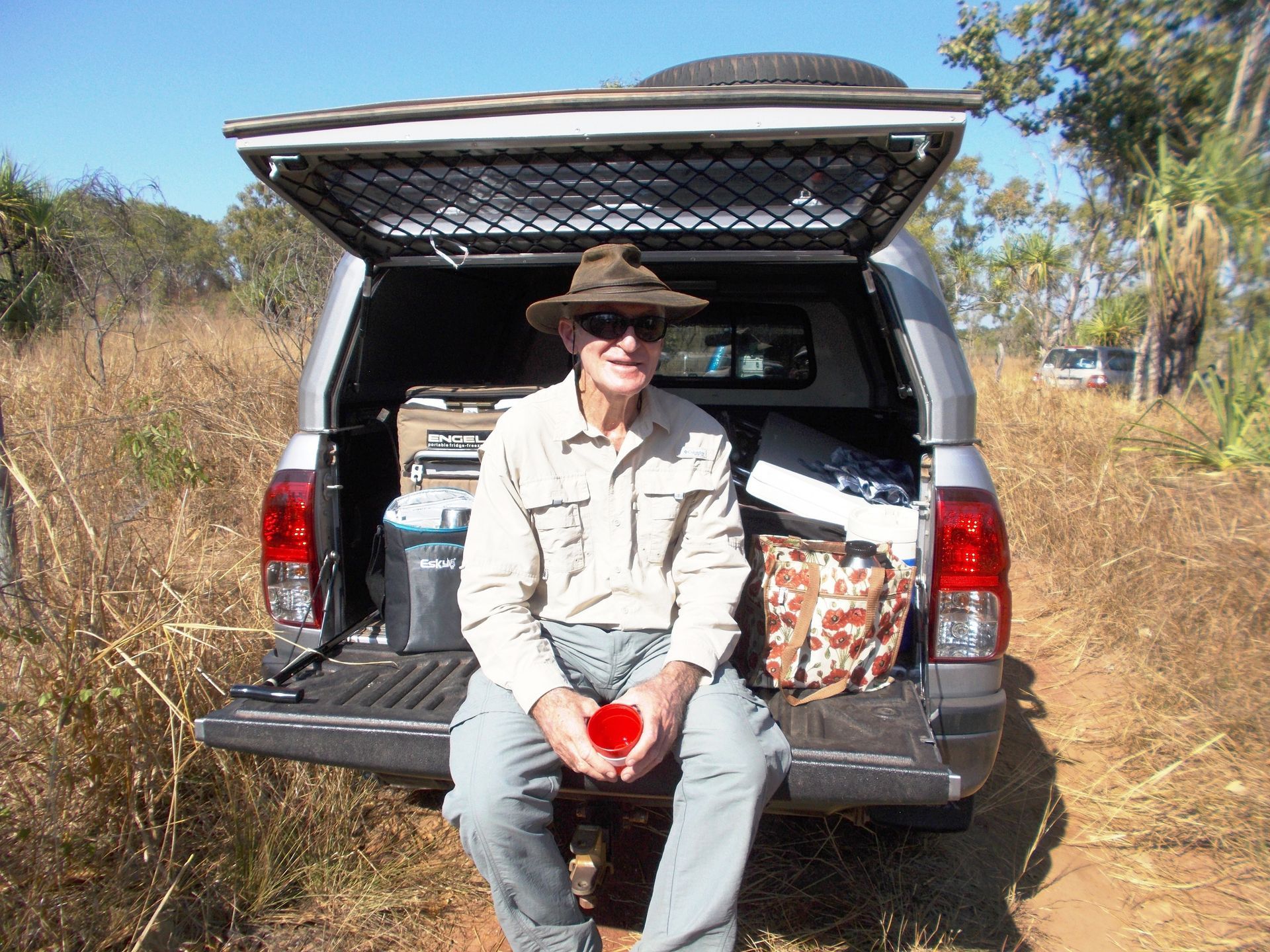 A man in a hat sits in the back of a truck