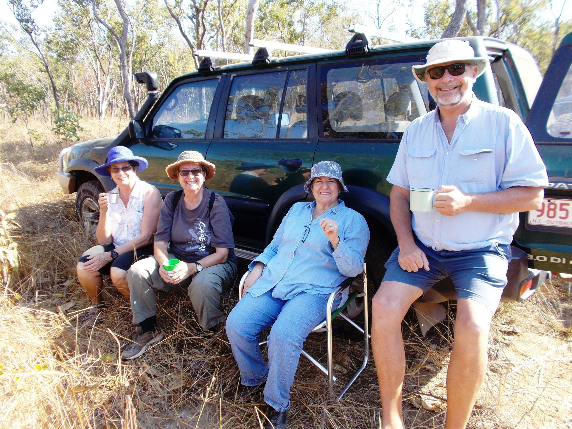 A group of people are sitting in front of a green suv
