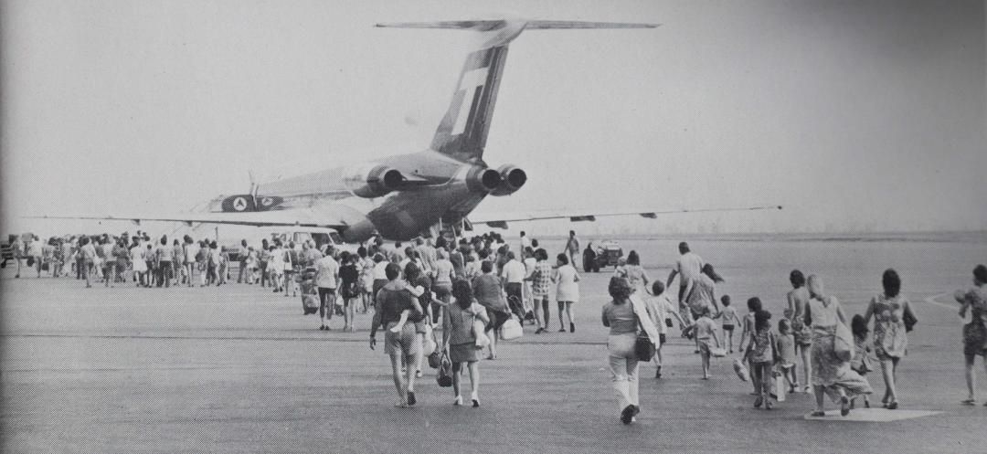 A black and white photo of people running towards a plane