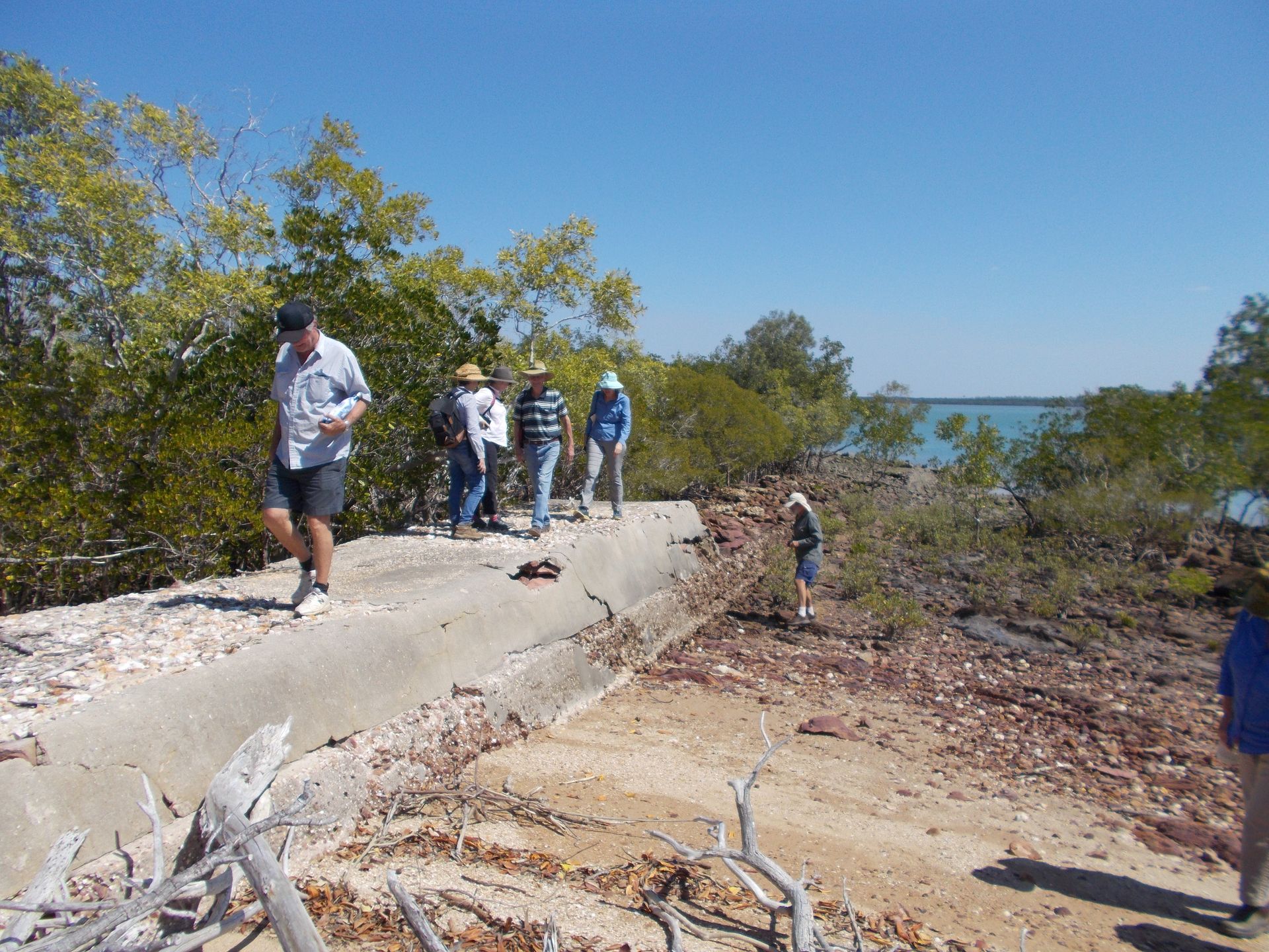 A group of people are walking on a path near the water.