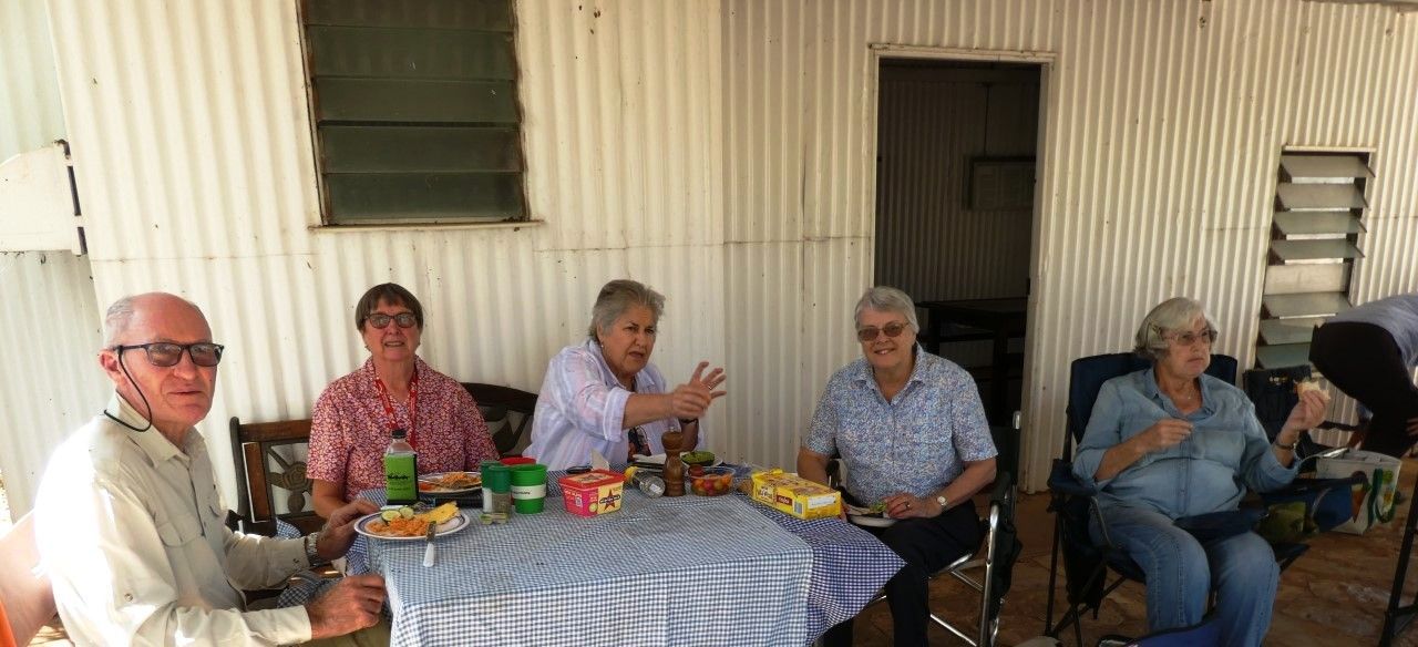 A group of people are sitting around a table eating food.