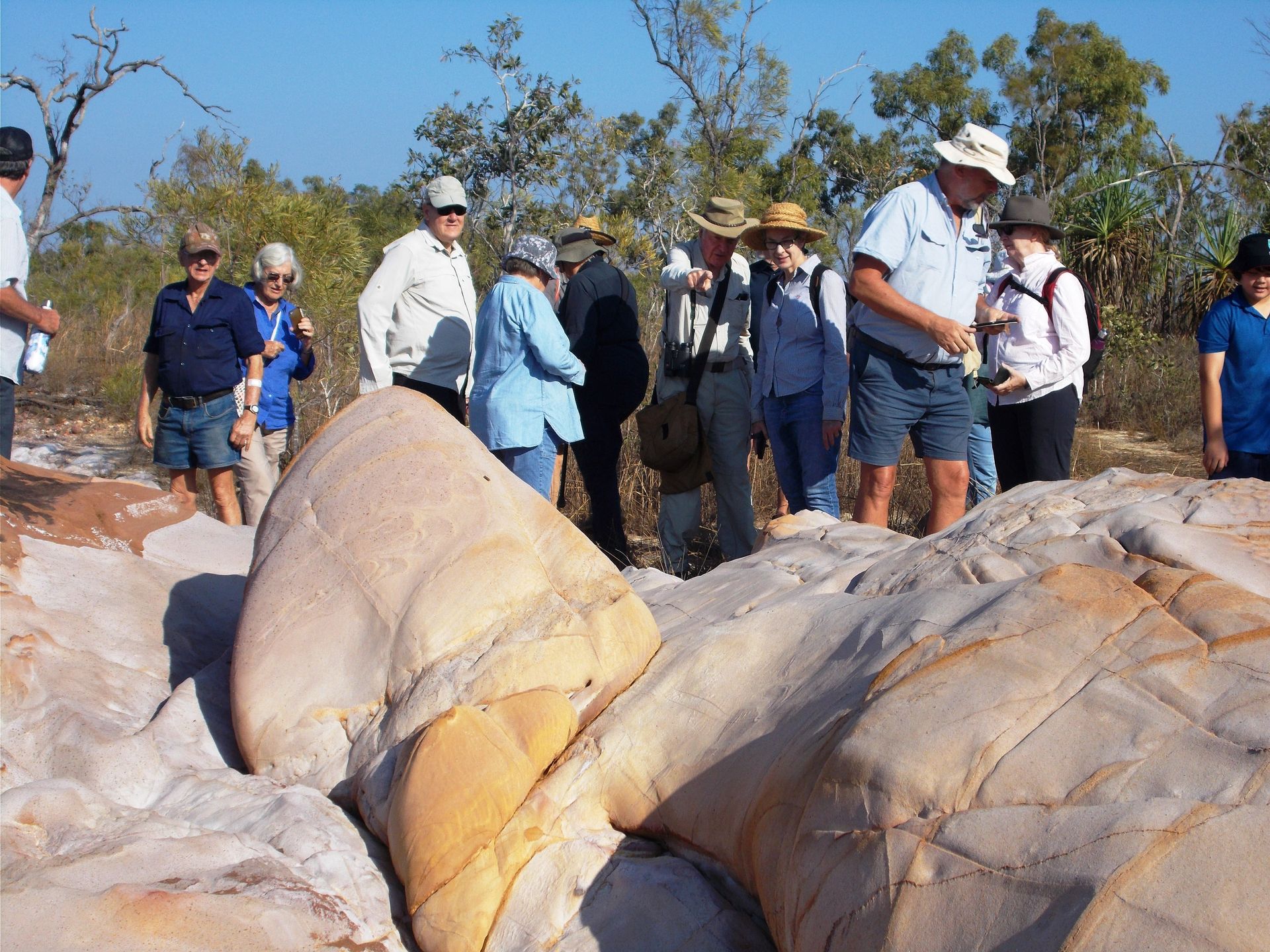 A group of people standing around a large rock