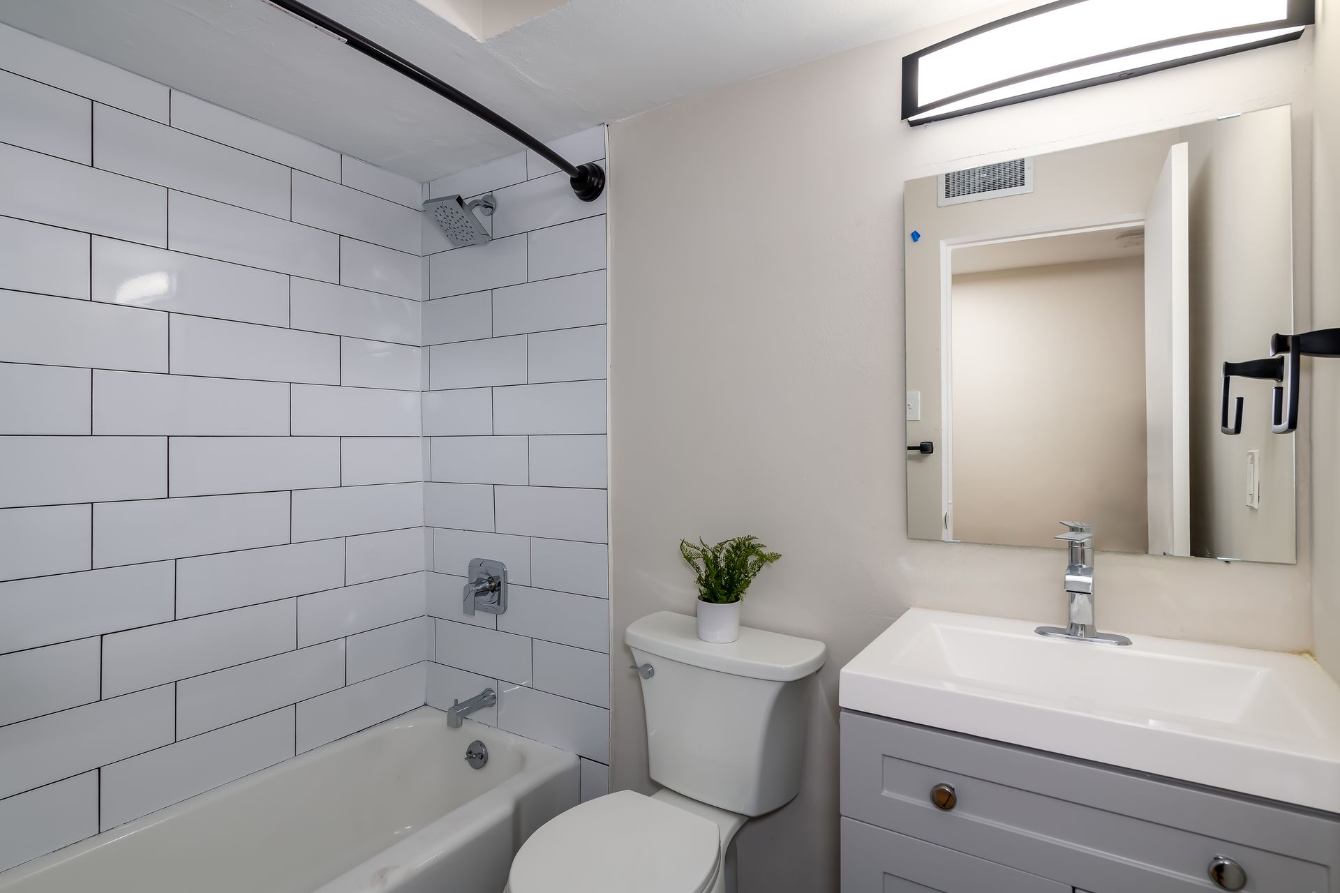 A bathroom with a toilet , sink , bathtub and mirror.