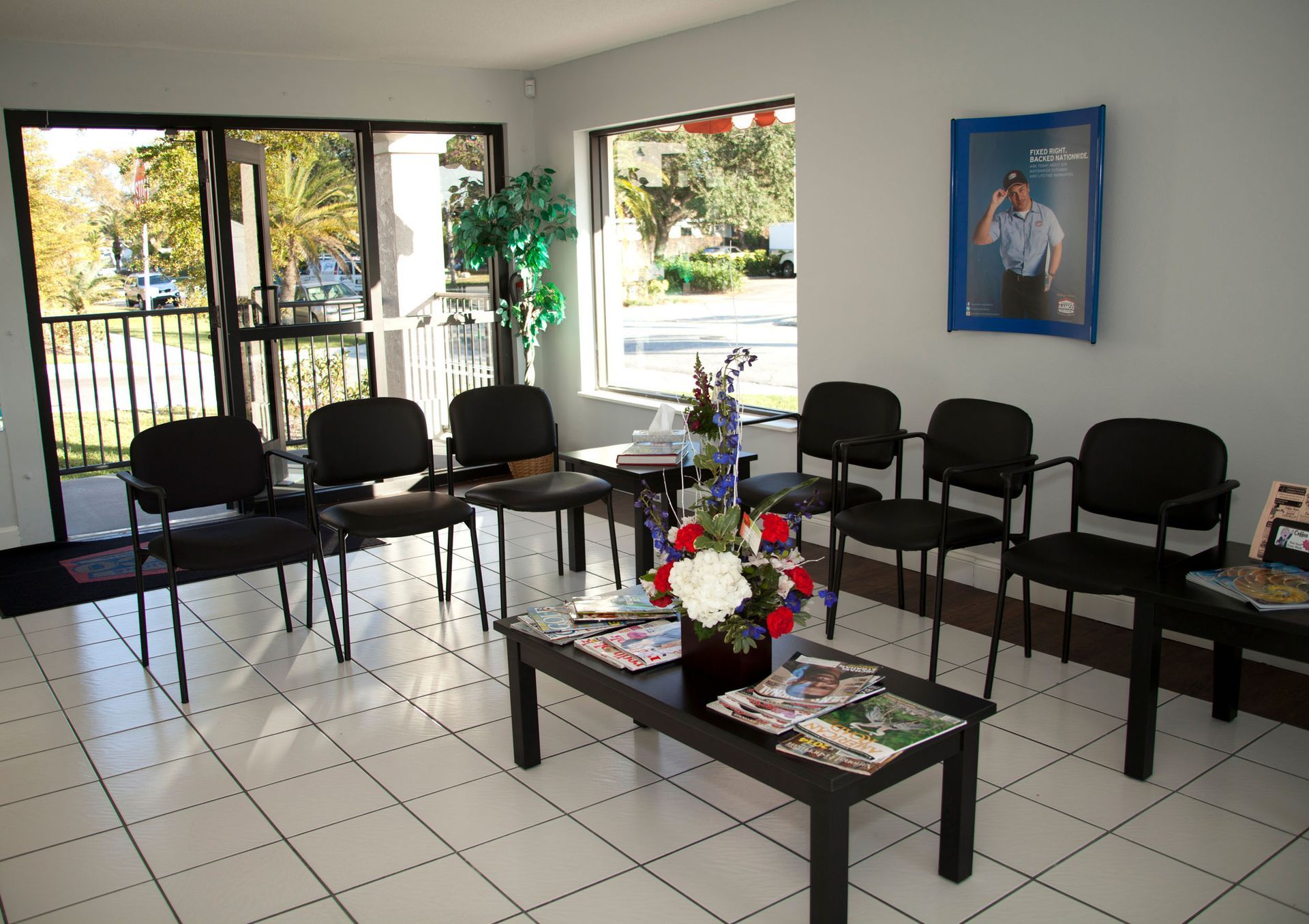 AAMCO Venice waiting room with black chairs, tiled floor, central coffee table, and wall art by large windows