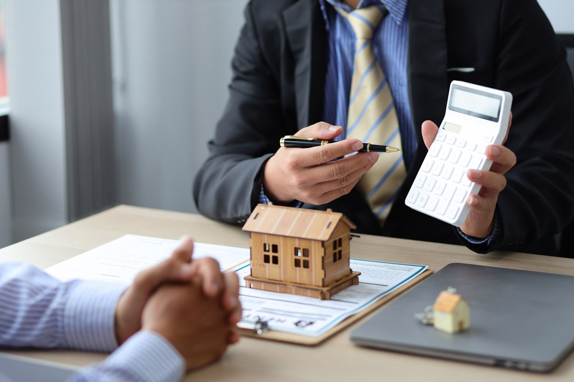 A man is sitting at a table holding a calculator and a pen.