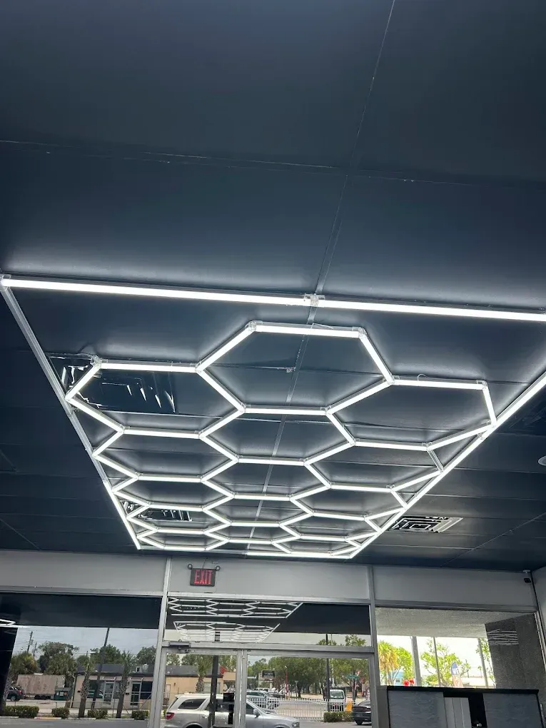 A black ceiling features a large, rectangular decorative light fixture consisting of a grid of illuminated hexagons.