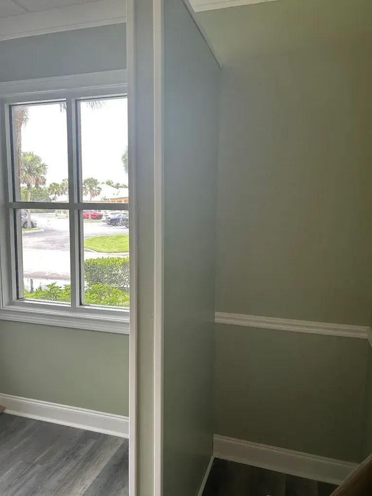 Interior view: a light green room with white trim. A window shows an outside view.