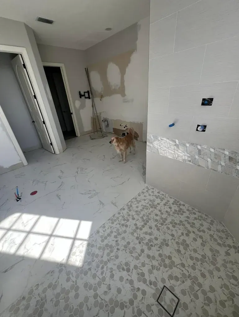 A golden-colored dog stands in a room under construction with new tile flooring and unfinished wall areas.