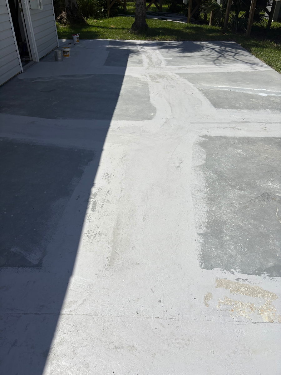 A rectangular concrete patio area under renovation, featuring a patchwork of light gray patches over joints and cracks.