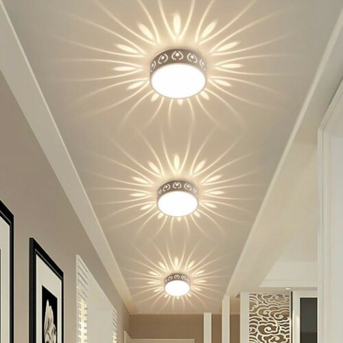 A hallway ceiling with three circular decorative lights casting sunburst-shaped patterns of light on the white ceiling.