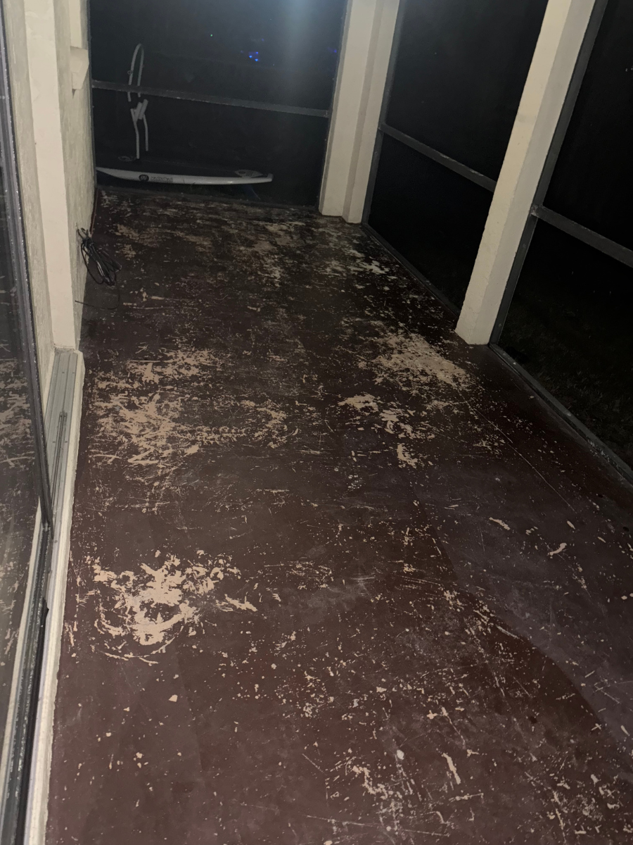 A dark balcony floor covered in scattered debris, dry leaves, and dirt, illuminated by dim lighting at night.