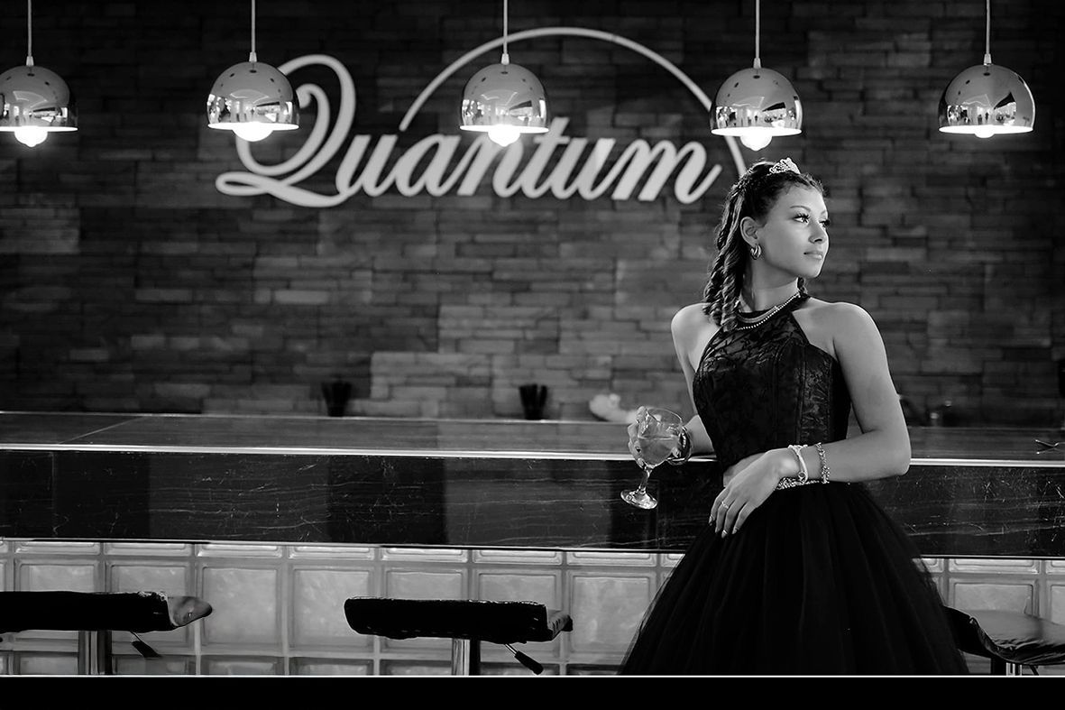 Mujer vestida formal sosteniendo una bebida en un bar llamado