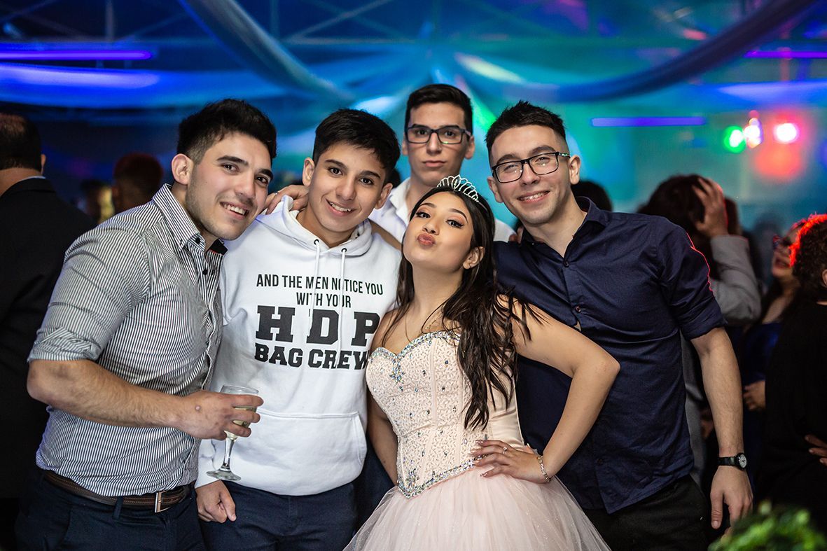 Cinco personas en una fiesta, posando para una foto. Una mujer con vestido formal está flanqueada por cuatro hombres.