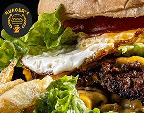 Primer plano de una hamburguesa con huevo frito, lechuga, tomate y queso, con un logo en la esquina.