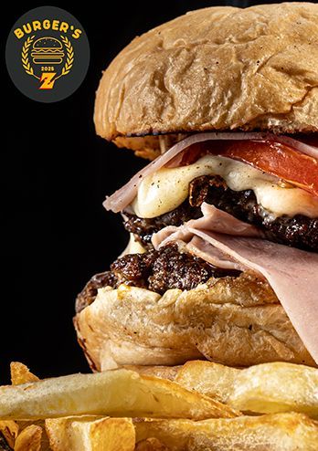 Hamburguesa doble con jamón, tomate, queso y papas fritas. El logo de la Z de Burger's en la esquina superior izquierda.