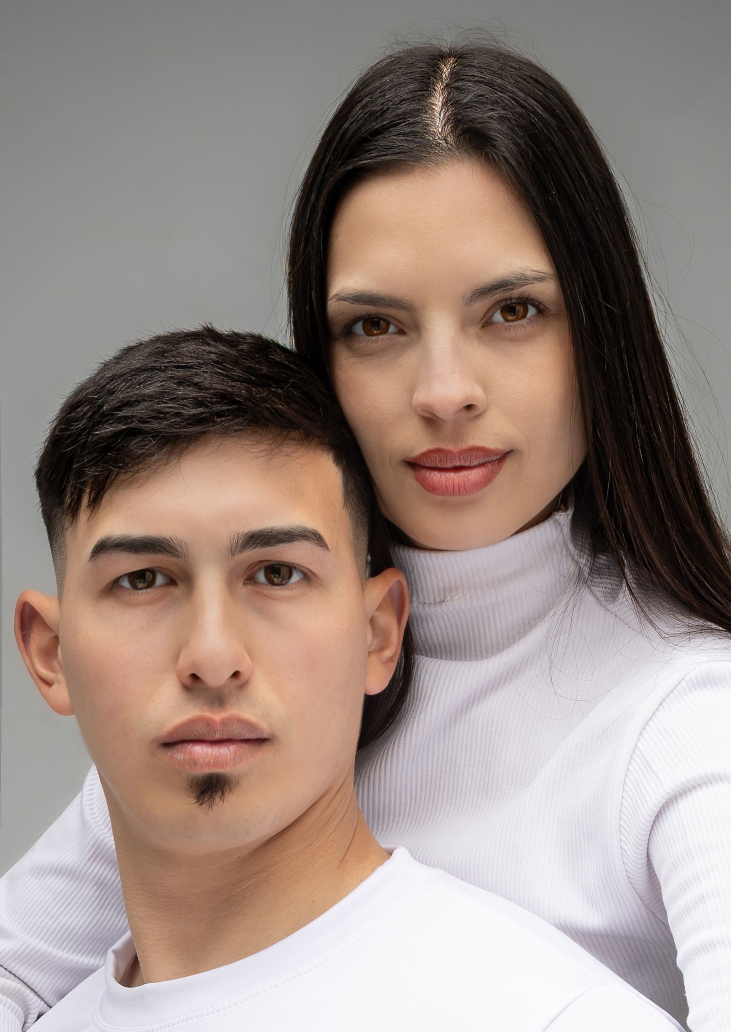 Un hombre y una mujer con cuellos de tortuga blancos, muy juntos.