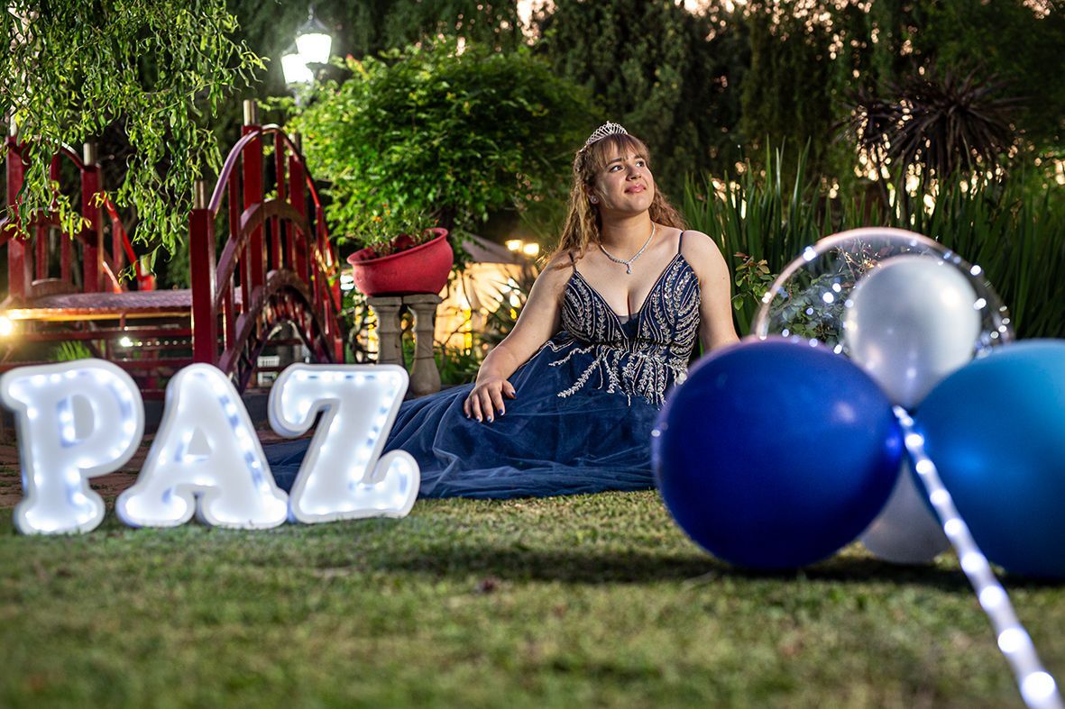 Mujer con un vestido azul y una corona, sentada cerca de letras iluminadas