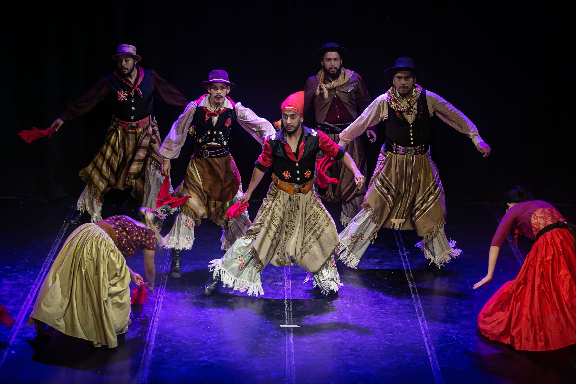 Bailarines con trajes típicos actúan en el escenario.