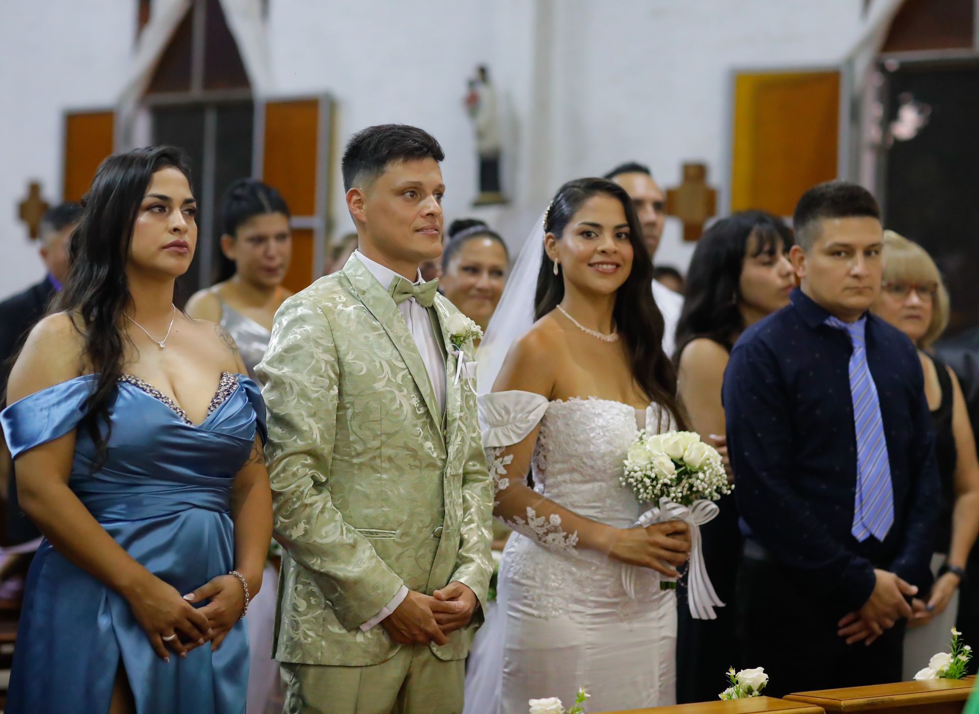 Ceremonia de boda. La novia con vestido blanco, el novio con traje verde y los invitados en una iglesia.