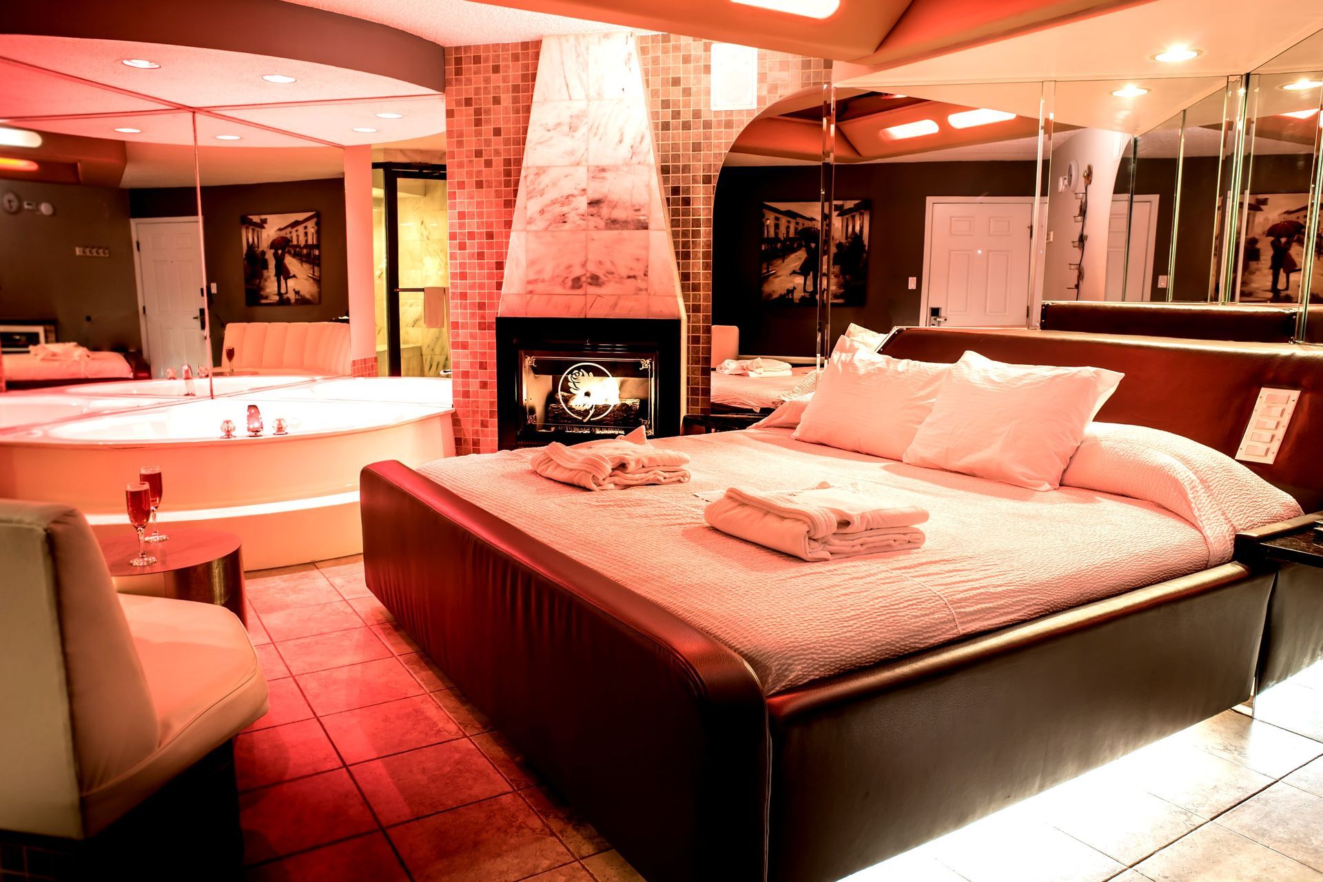 Romantic hotel room with a bed, fireplace, and jacuzzi. Red lighting creates a warm atmosphere.