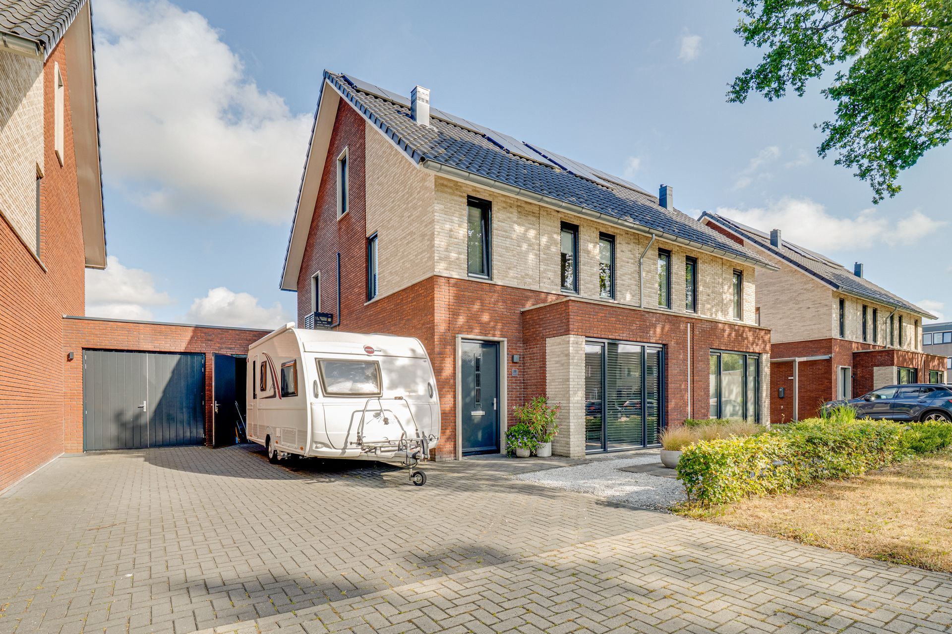 Rij moderne bakstenen rijtjeshuizen met een witte bestelbus geparkeerd op een geplaveide oprit.