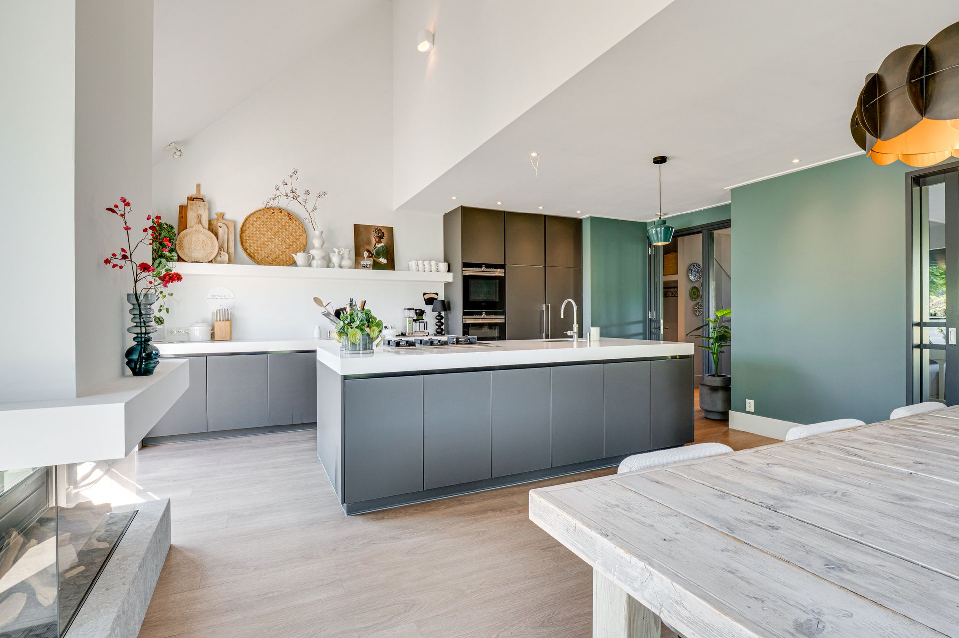 Lichte, moderne keuken met grijs kookeiland, witte aanrechtbladen en lichte houten vloeren.