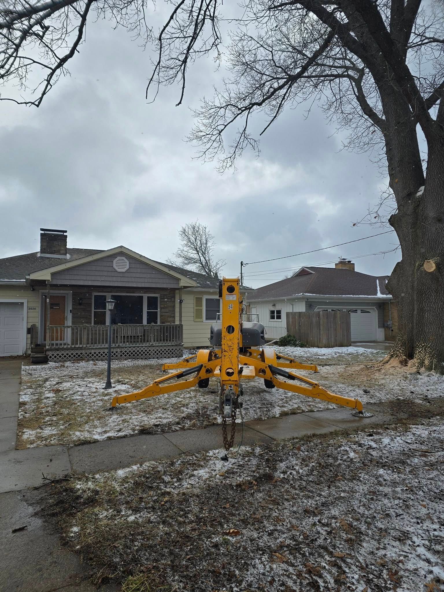Yellow utility tripod on a snowy residential street with houses in the background