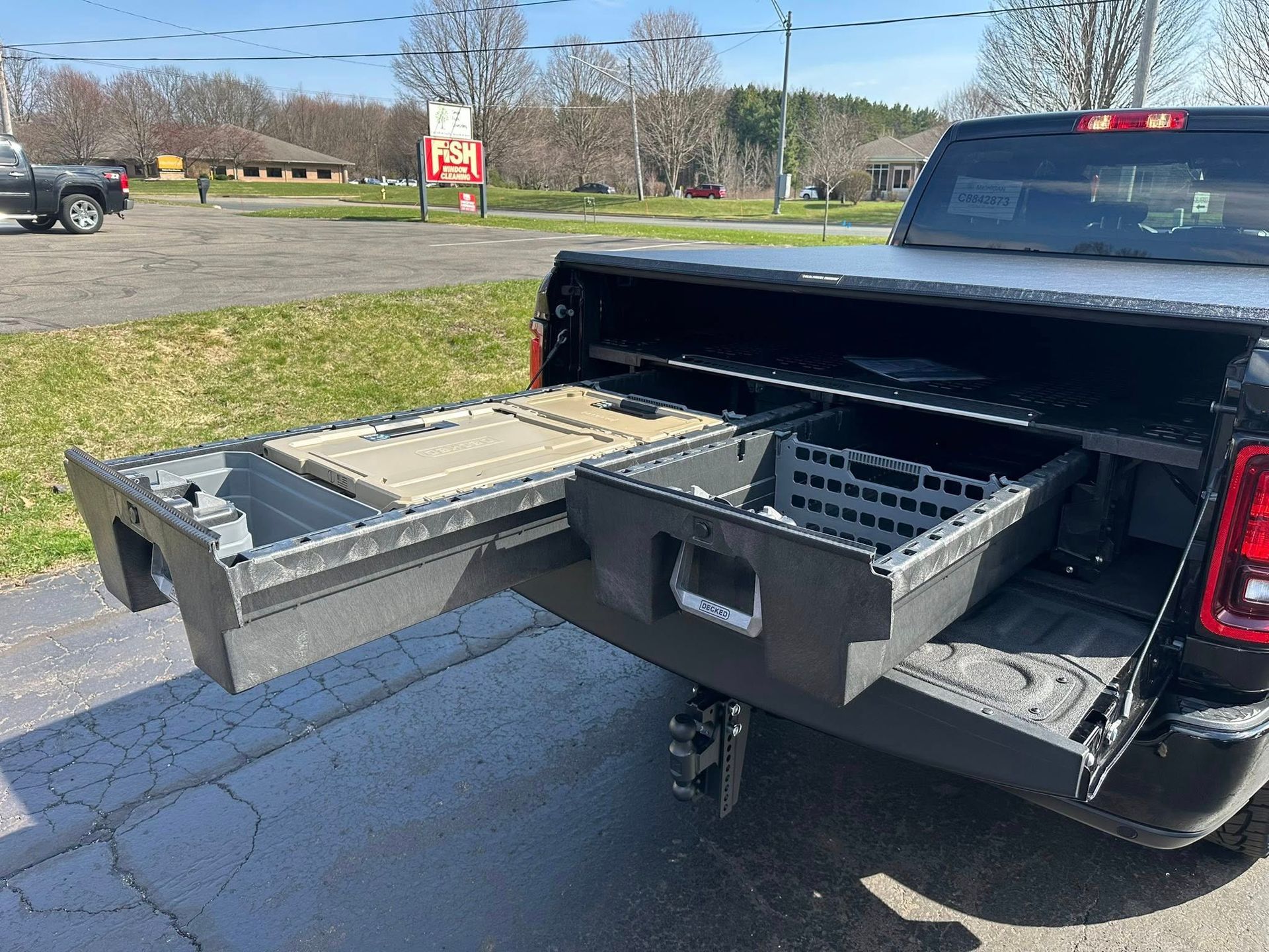 Black pickup truck with tailgate organizer trays extended in a parking lot under bright daylight