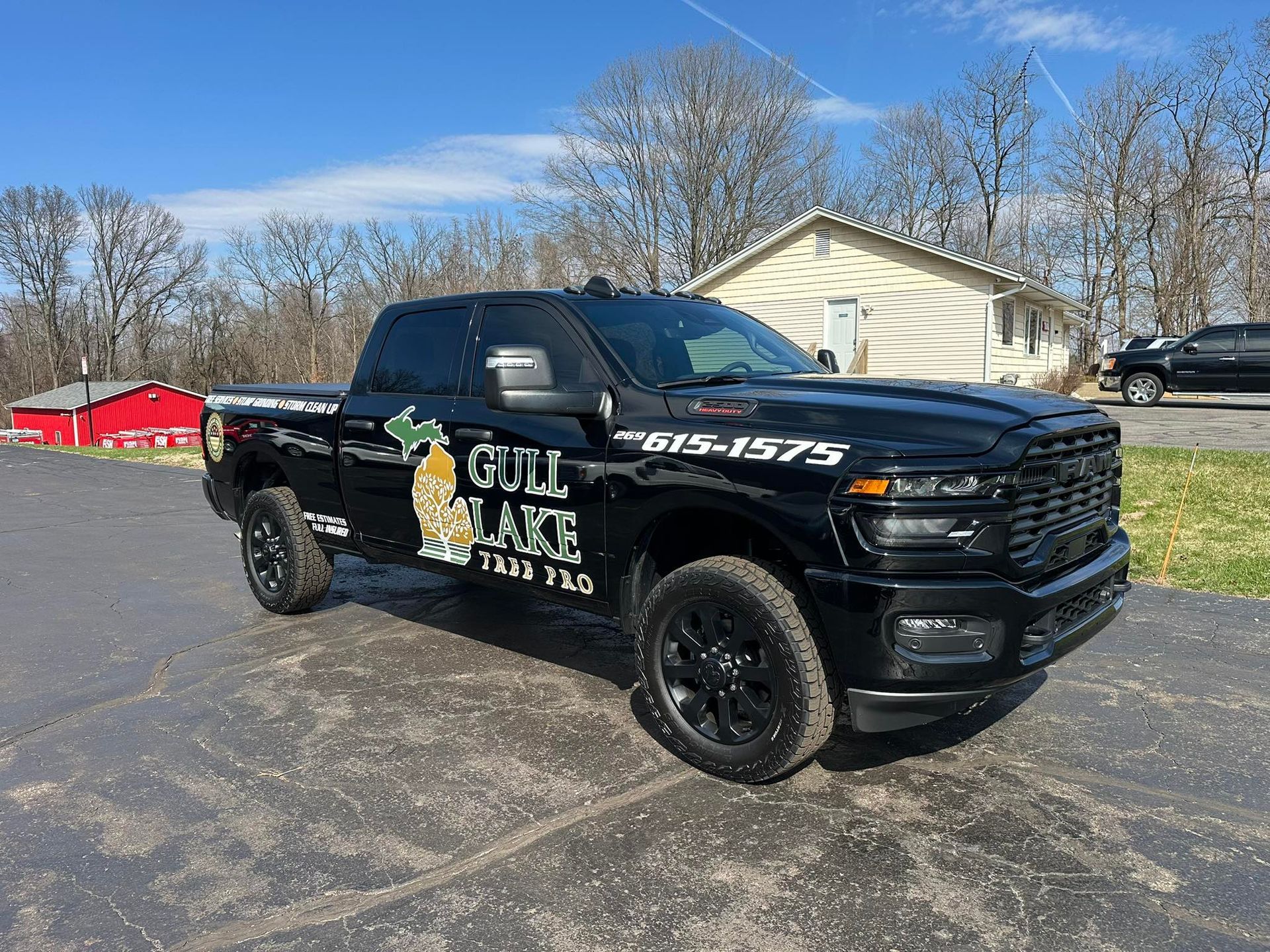 Black pickup truck with company decals parked on a lot in front of a building on a sunny day