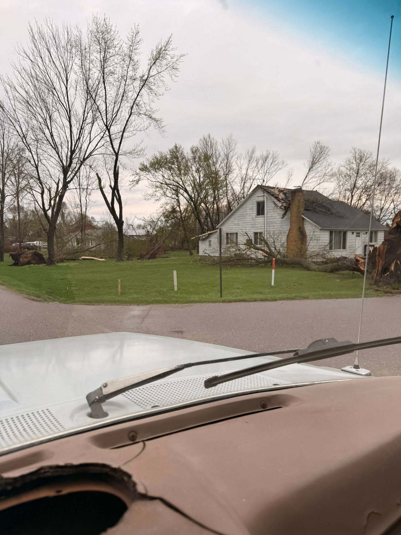 View from inside a car of a suburban house and lawn on a cloudy day