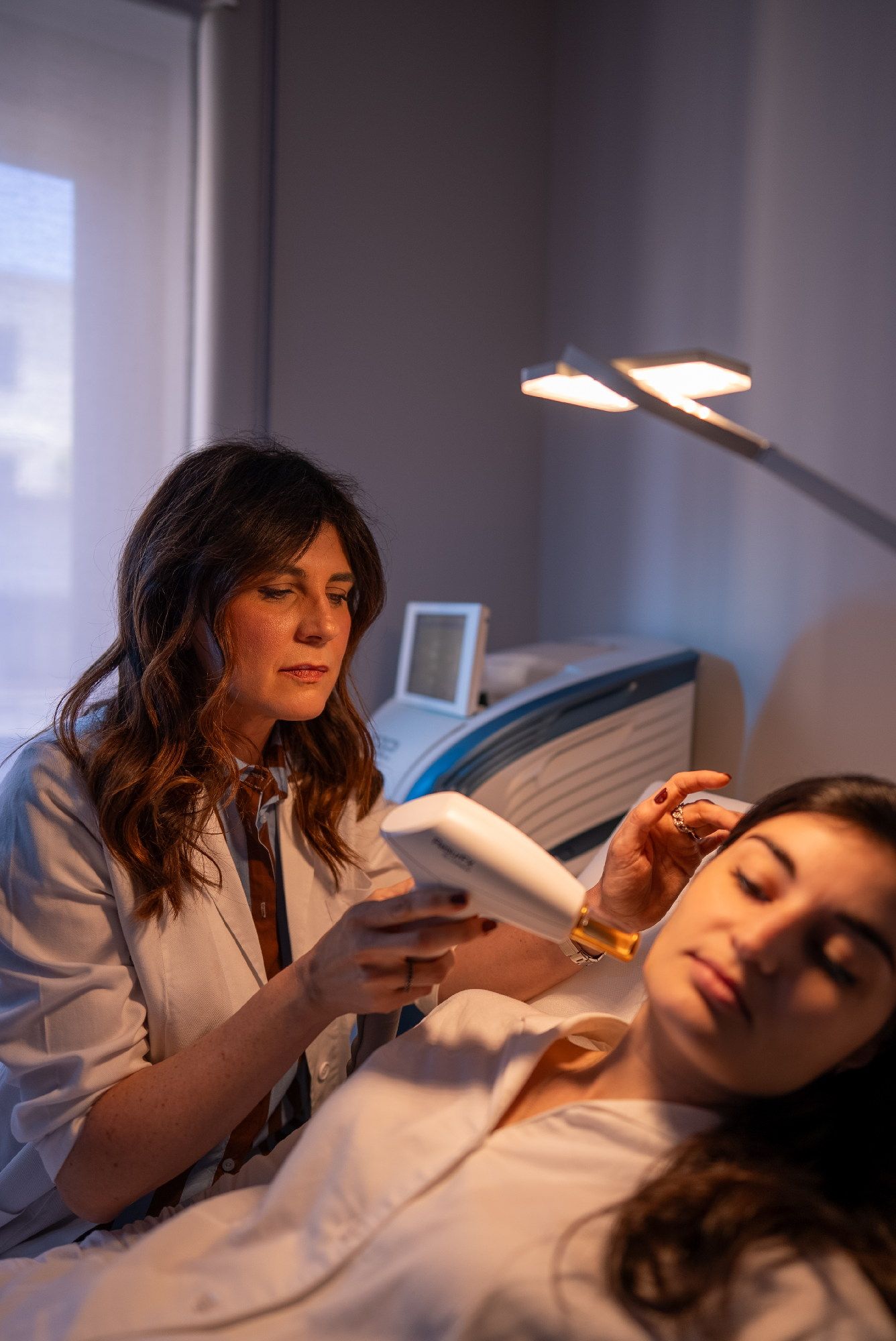 Una donna è sdraiata su un letto mentre un dermatologo la esamina a Genova