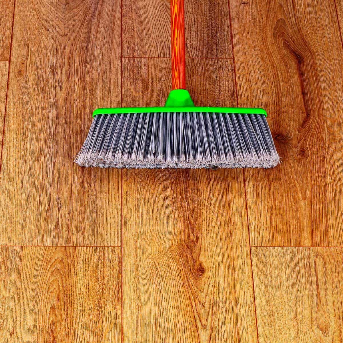 Green and gray broom on a wooden floor.